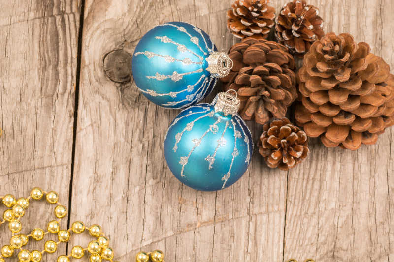 木色桌面上蓝色的球型装饰品和松子圣诞装饰品