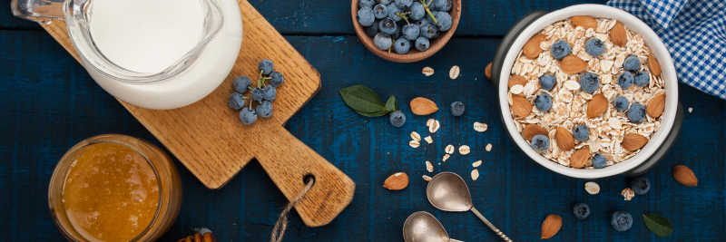 深蓝色木质背景的燕麦片牛奶蓝莓蜂蜜和杏仁