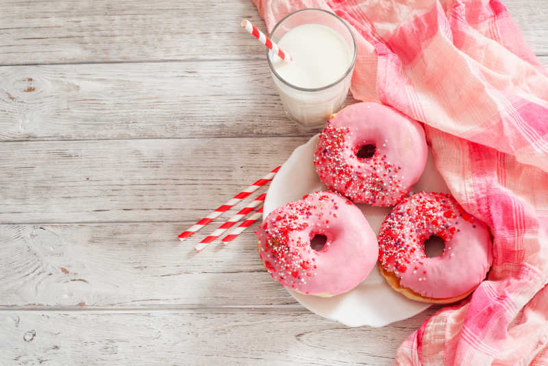 粉色甜甜圈与一杯牛奶和樱桃粉红色的糖衣
