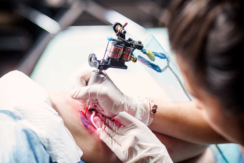 纹身师傅用纹身机在帮女子纹身