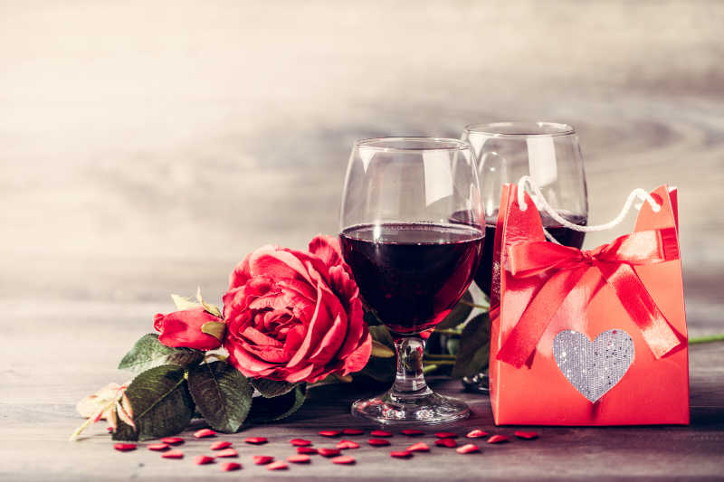 两杯红葡萄酒用红心装饰在木桌上