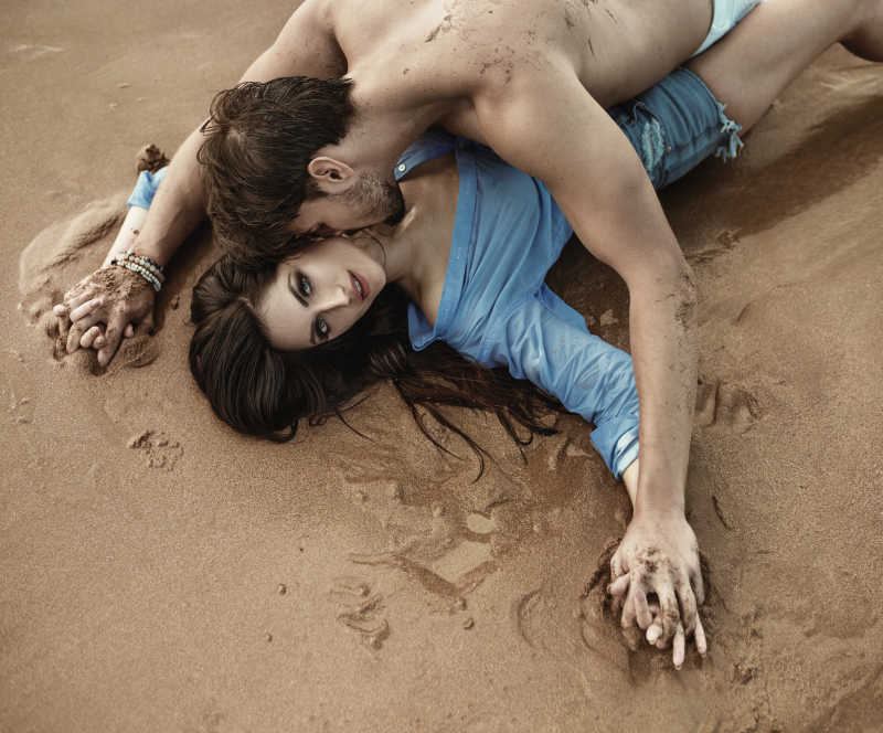 一对年轻性感情侣躺在沙滩上