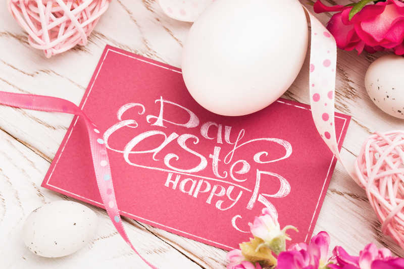 白色木制背景粉色问候标签和复活节装饰彩蛋
