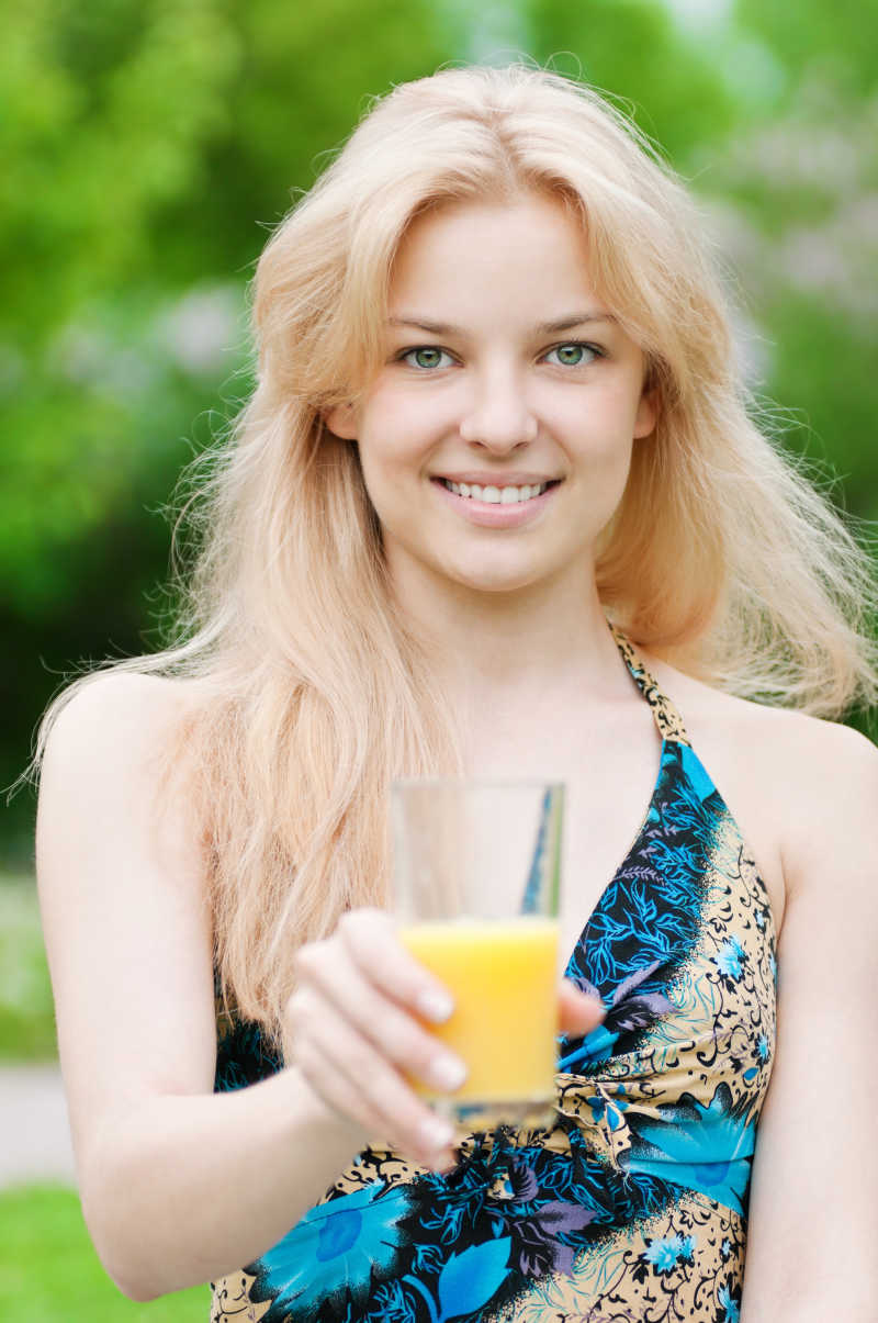微笑着喝桔子汁的年轻女人