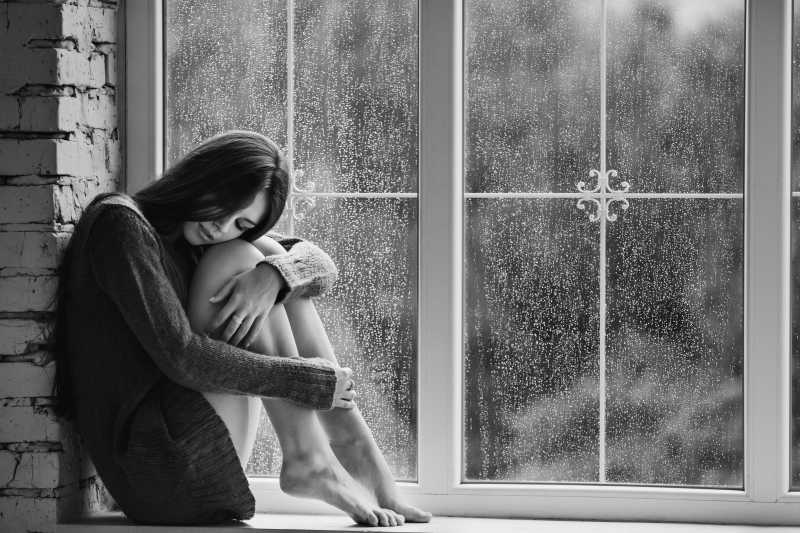 下雨天一个美丽的年轻女子独自坐在窗边