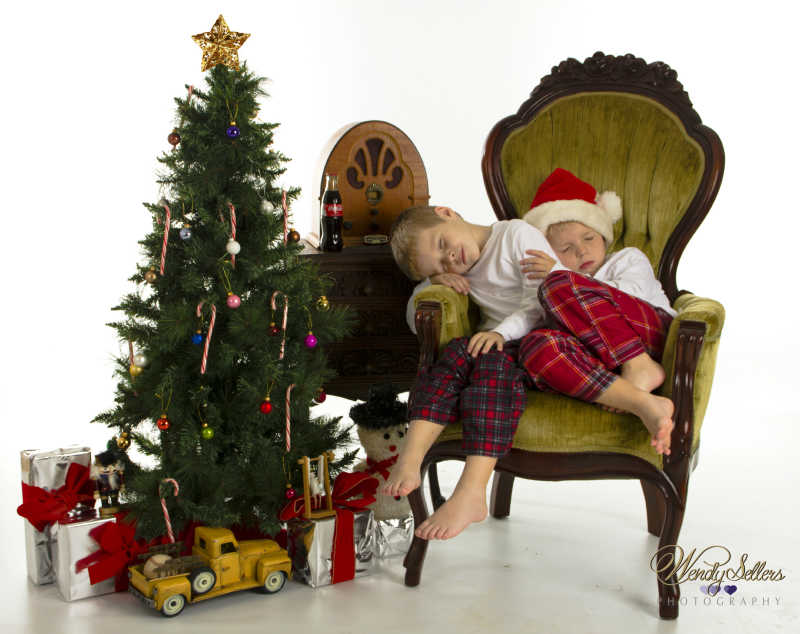 圣诞树旁的椅子上睡着的孩子