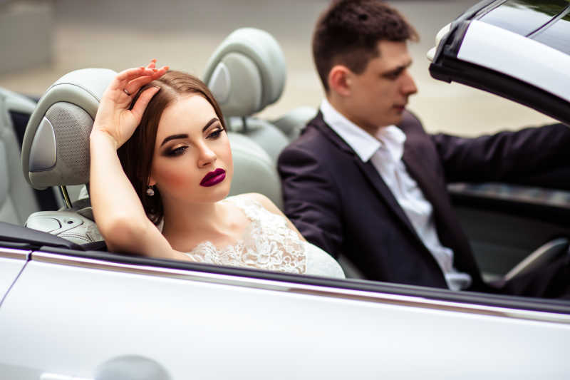 坐在跑车里的帅气新郎和美丽的新娘