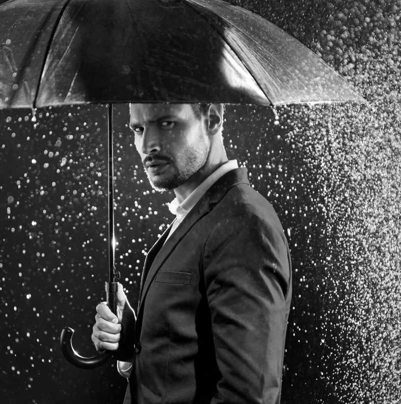 雨中撑着伞的男子的黑白肖像