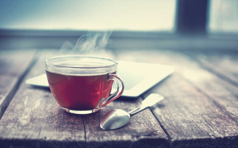 木桌上的一杯热红茶和平板