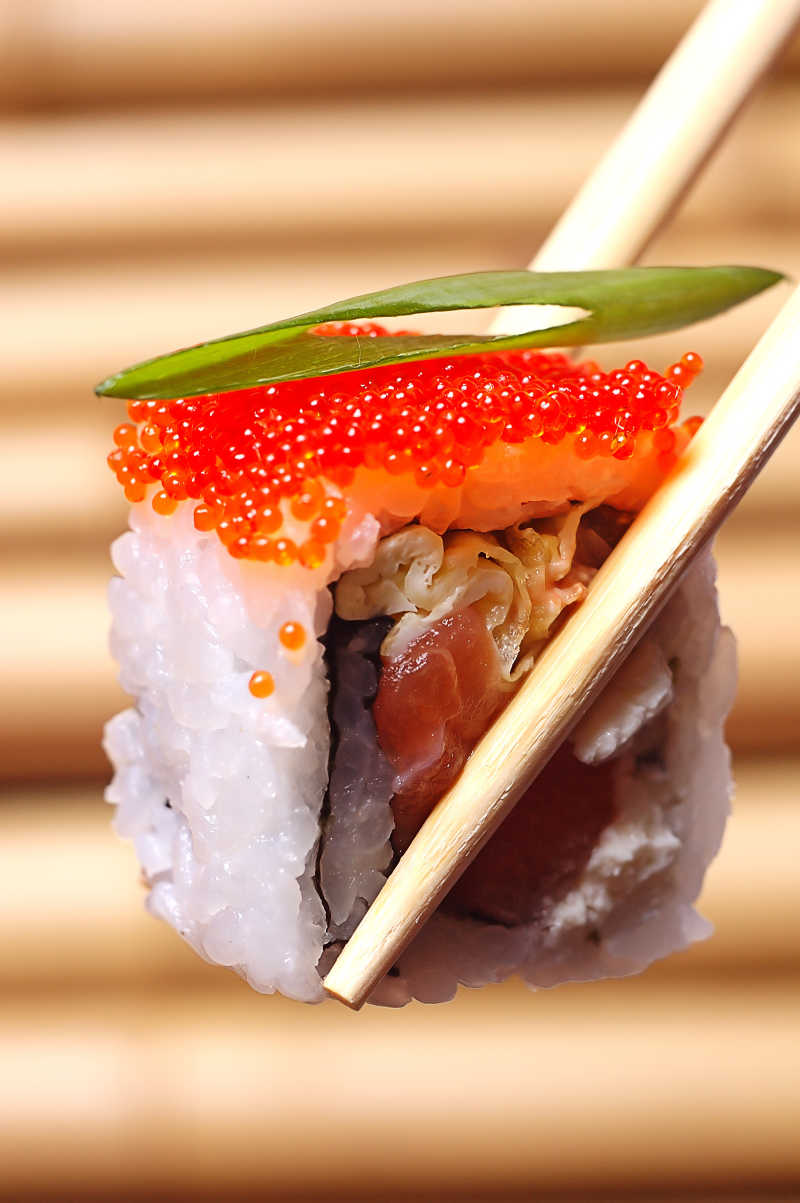 筷子上夹着鱼子酱寿司特写