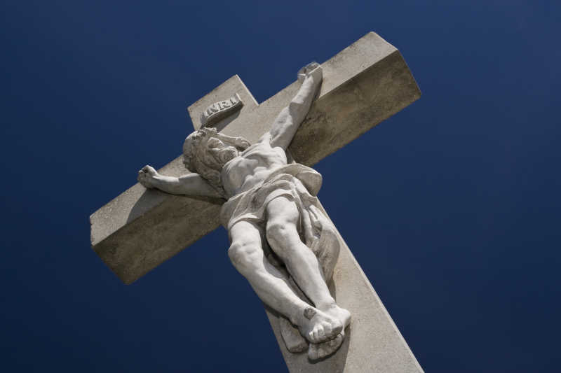 深蓝色背景下耶稣被钉十字架的石像