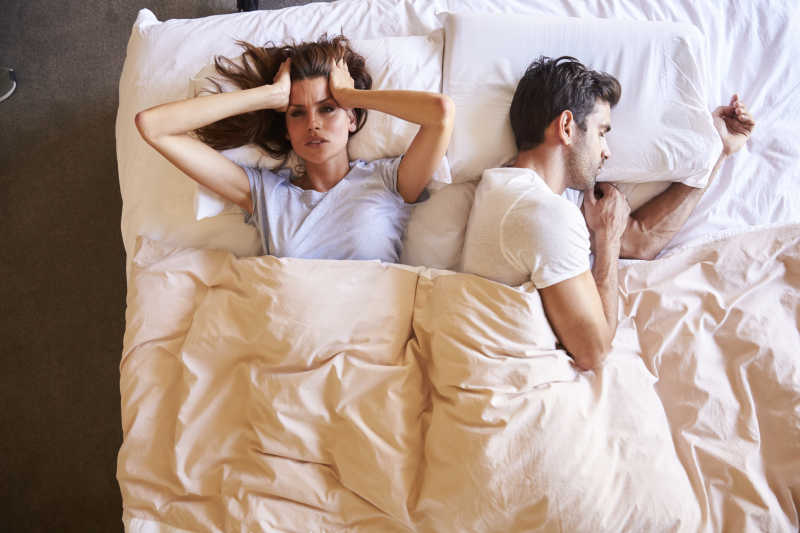 崩溃的妻子和睡觉的丈夫躺在床上