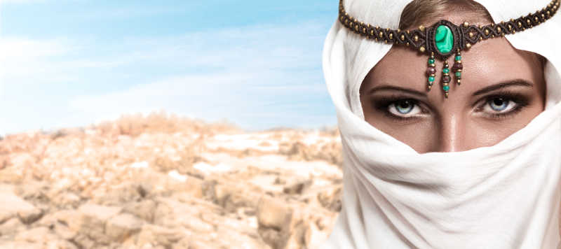 沙漠背景下戴着白色头巾面纱的年轻漂亮女人