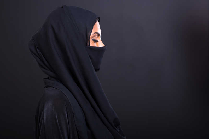 黑色背景下戴着黑色头巾面纱的女人闭着眼