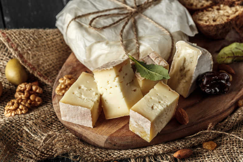木桌上切好的奶酪大枣和包装好的奶酪