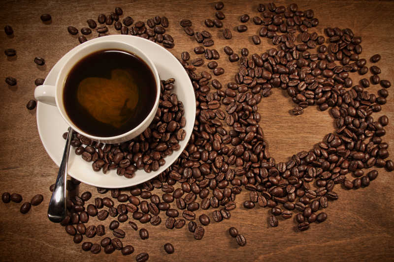 木质背景咖啡豆心形和一杯咖啡