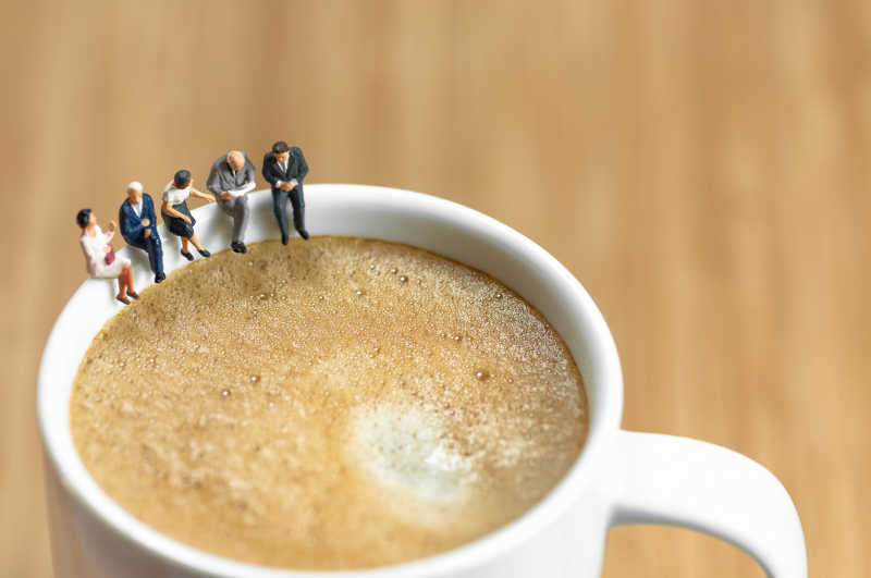 有咖啡杯上休息的小型商务团队模型