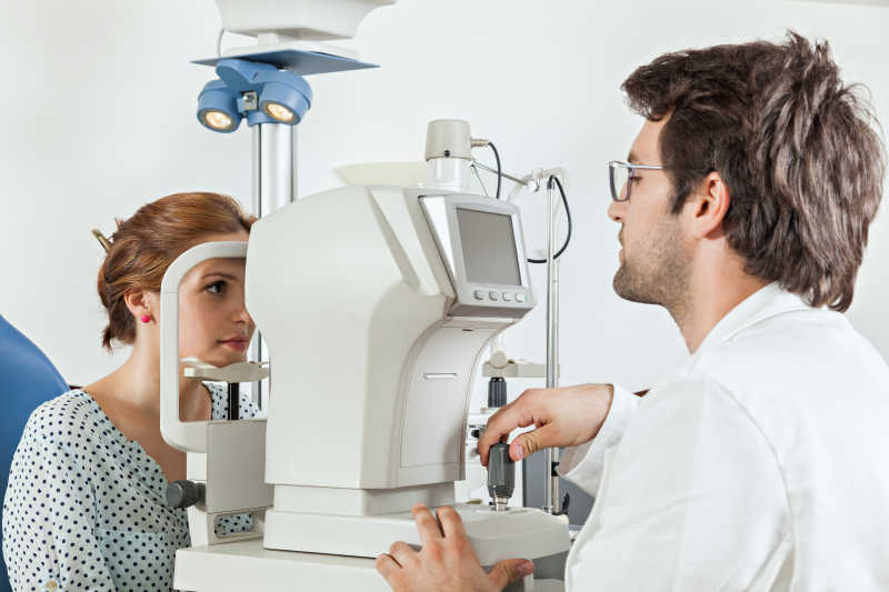 女人在眼科眼试验机上接受男医生的测试