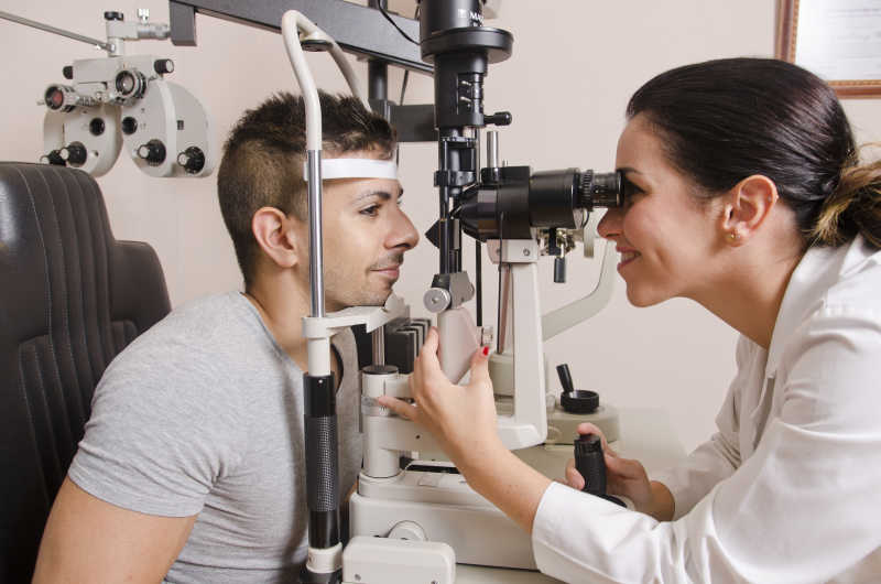 操作光学检查设备给患者做眼睛检查的女人