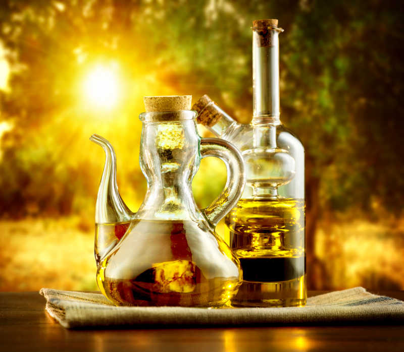 阳光下树林里桌子上的玻璃瓶装好的橄榄油