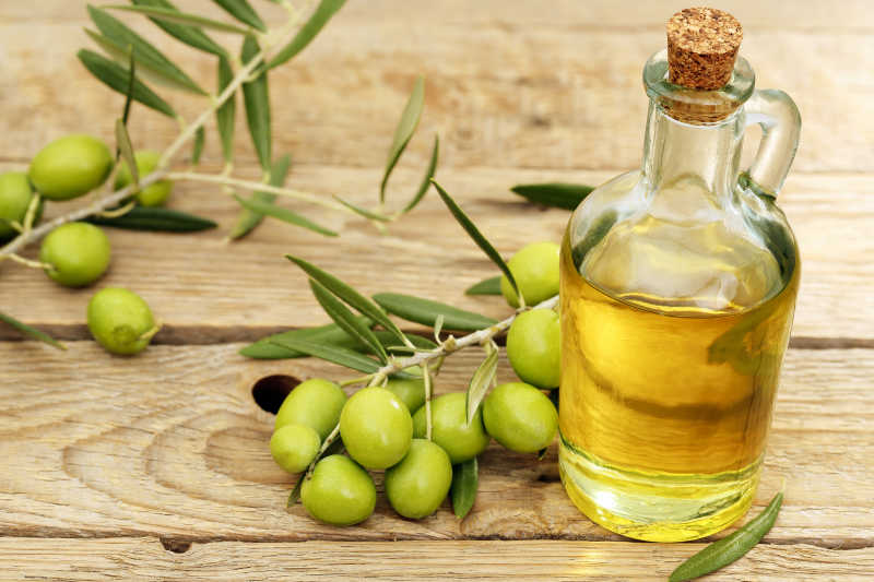 木桌上玻璃瓶里的橄榄油和橄榄树树枝