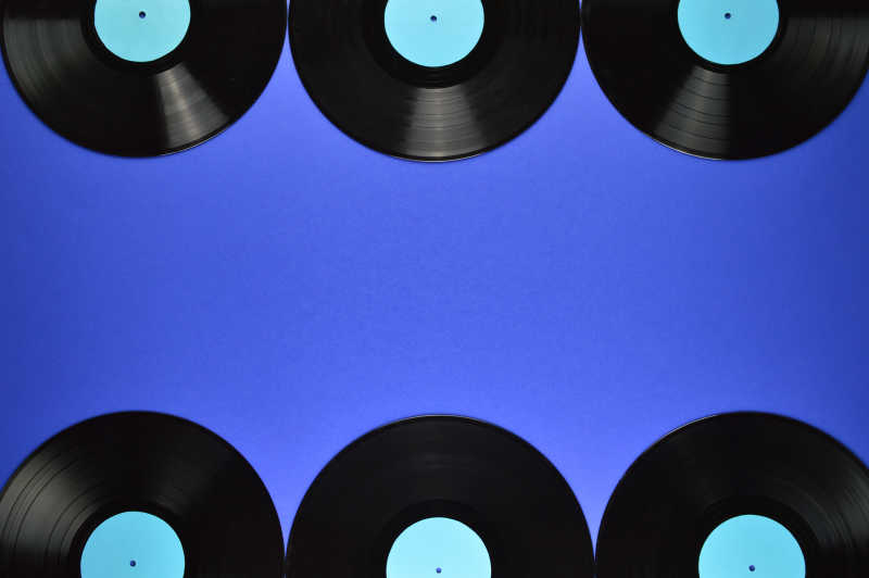 蓝色背景下排列整齐的旧黑乙烯基唱片