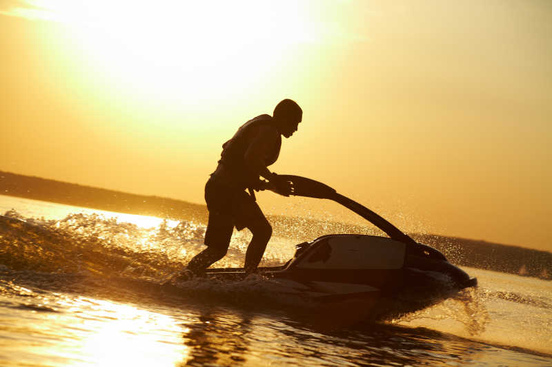 驾驶着摩托艇的人在夕阳下的剪影