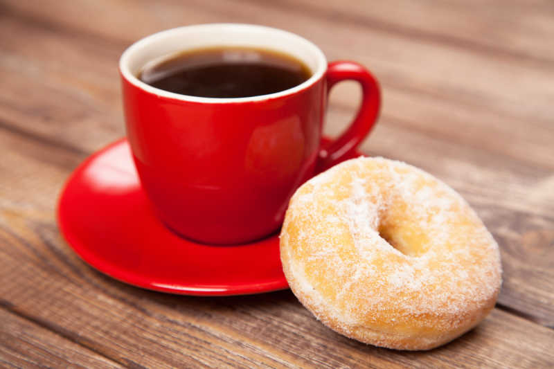 木桌上的美味的甜甜圈和一杯咖啡