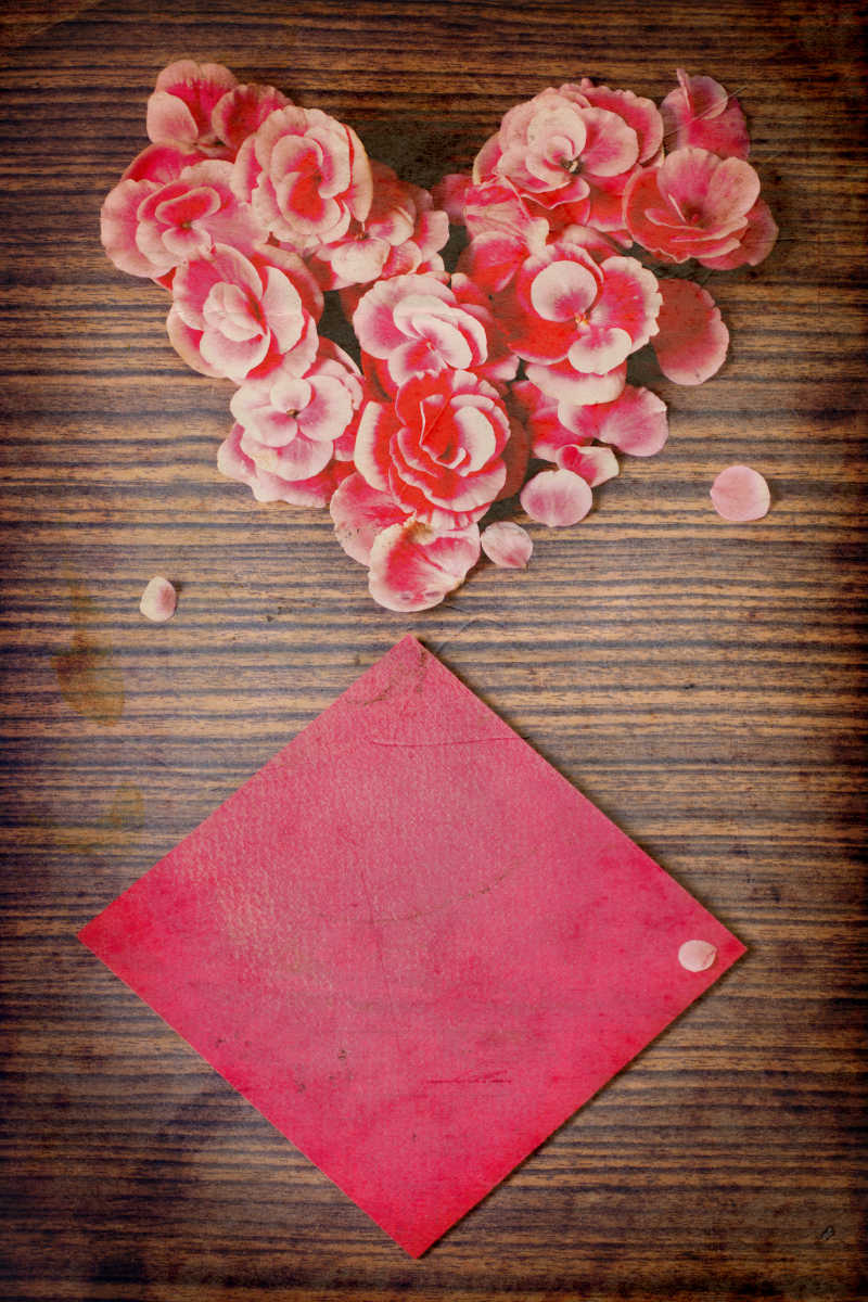 木制餐桌上的心形鲜花和红纸