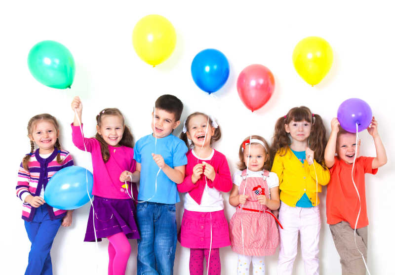 一群快乐的孩子在白墙上放气球