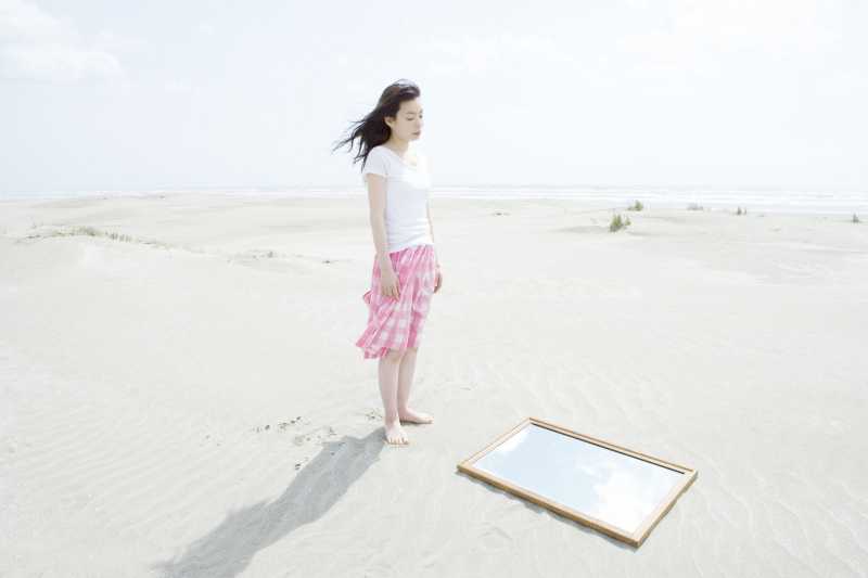 走在海滩上的女孩发现一面镜子