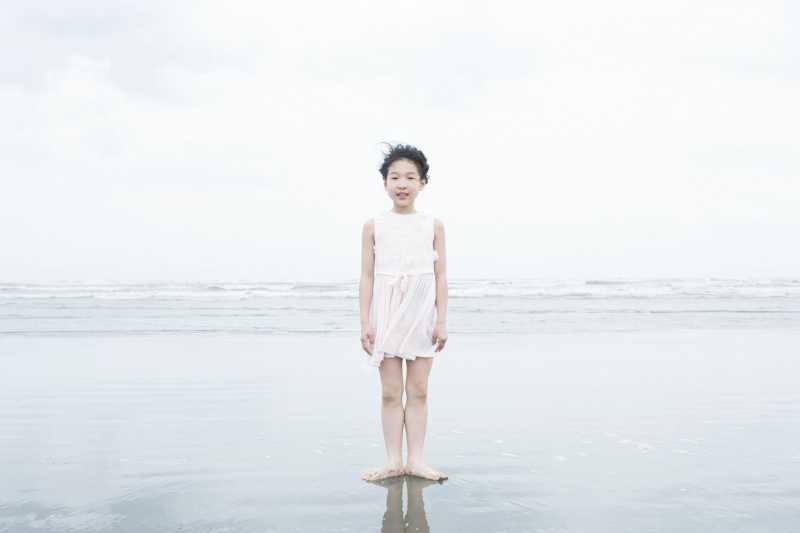 光脚站立在海滩上的小女孩