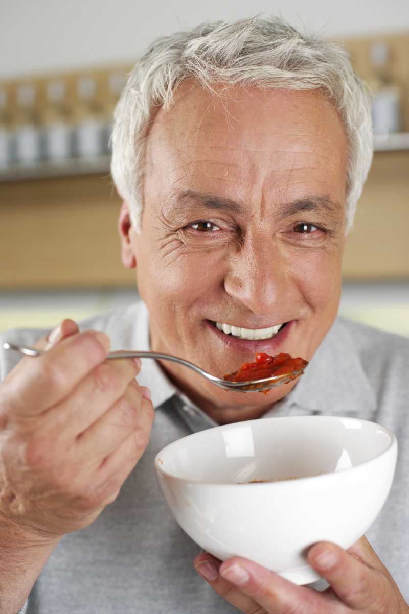 头发灰白的男人正在品尝番茄酱
