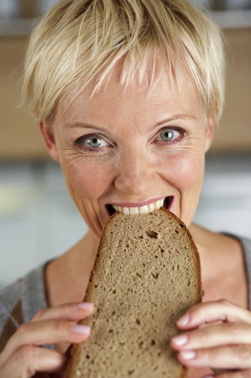 成熟的金发女郎咬着一片烤面包