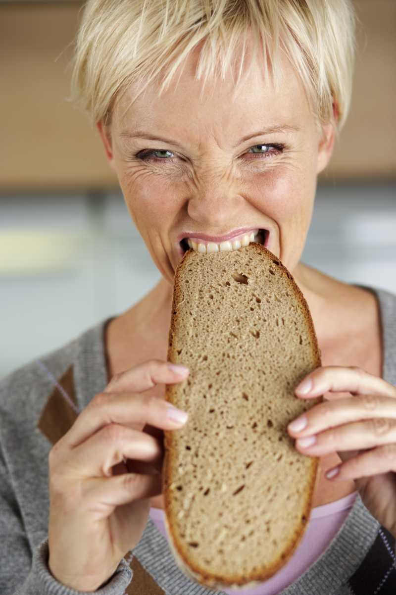 成熟的金发女郎咬着一片面包