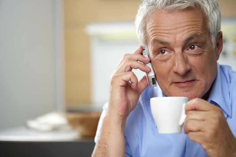 白发的男人一边喝着咖啡一边打电话