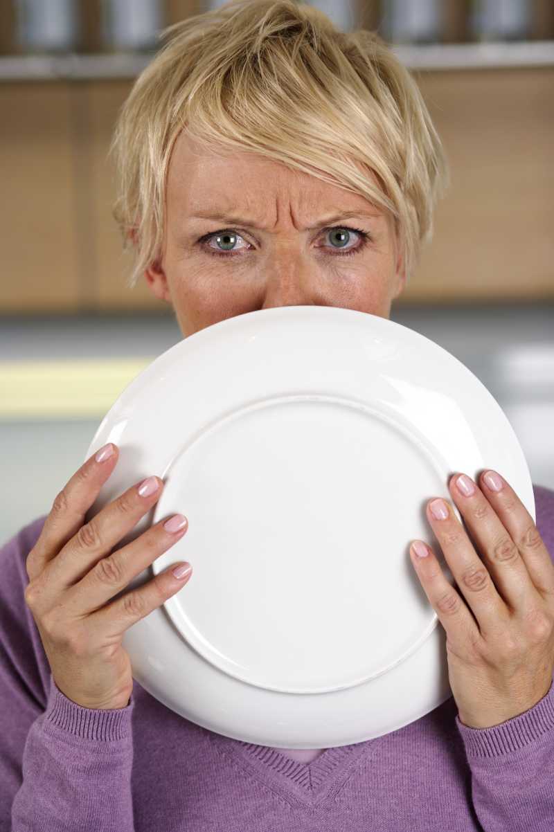 一个金发女人愤怒地盯着盘子的边缘