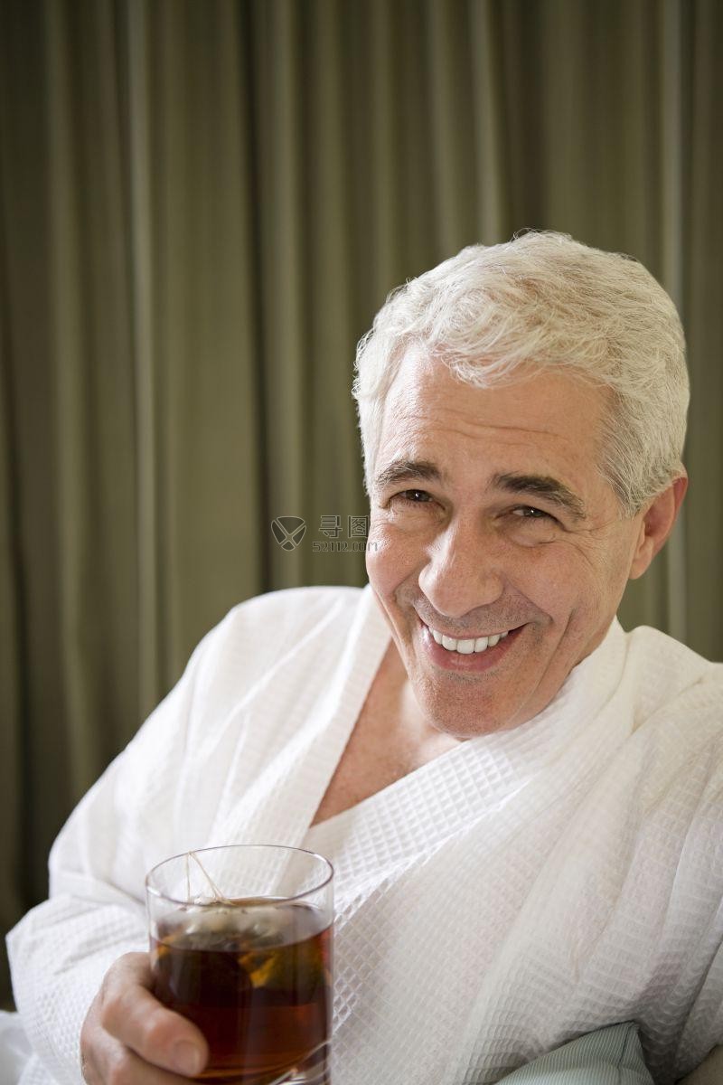 穿着浴袍喝茶的开心的中年人