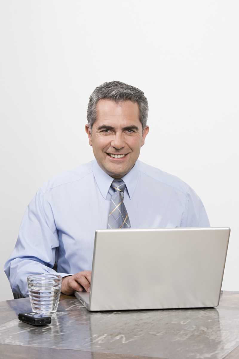 电脑前面的微笑的商人