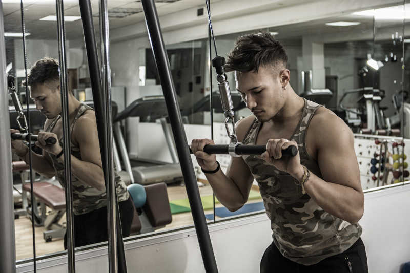 年轻人在健身器材上训练臂肌