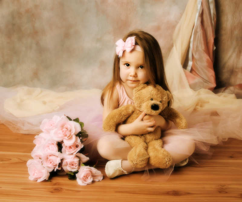 旁边放着粉红色玫瑰抱着泰迪熊玩具的小女孩摄影
