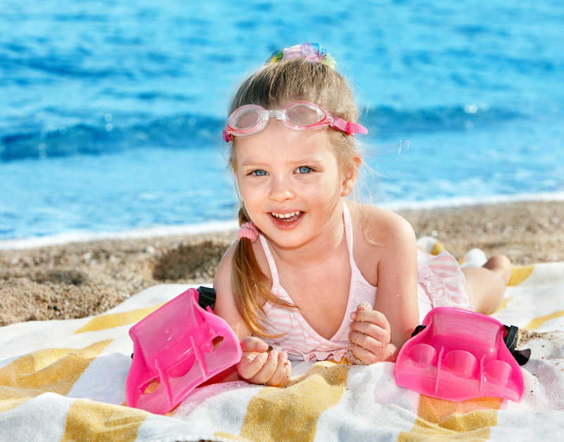 趴在海滩上玩的快乐的小女孩