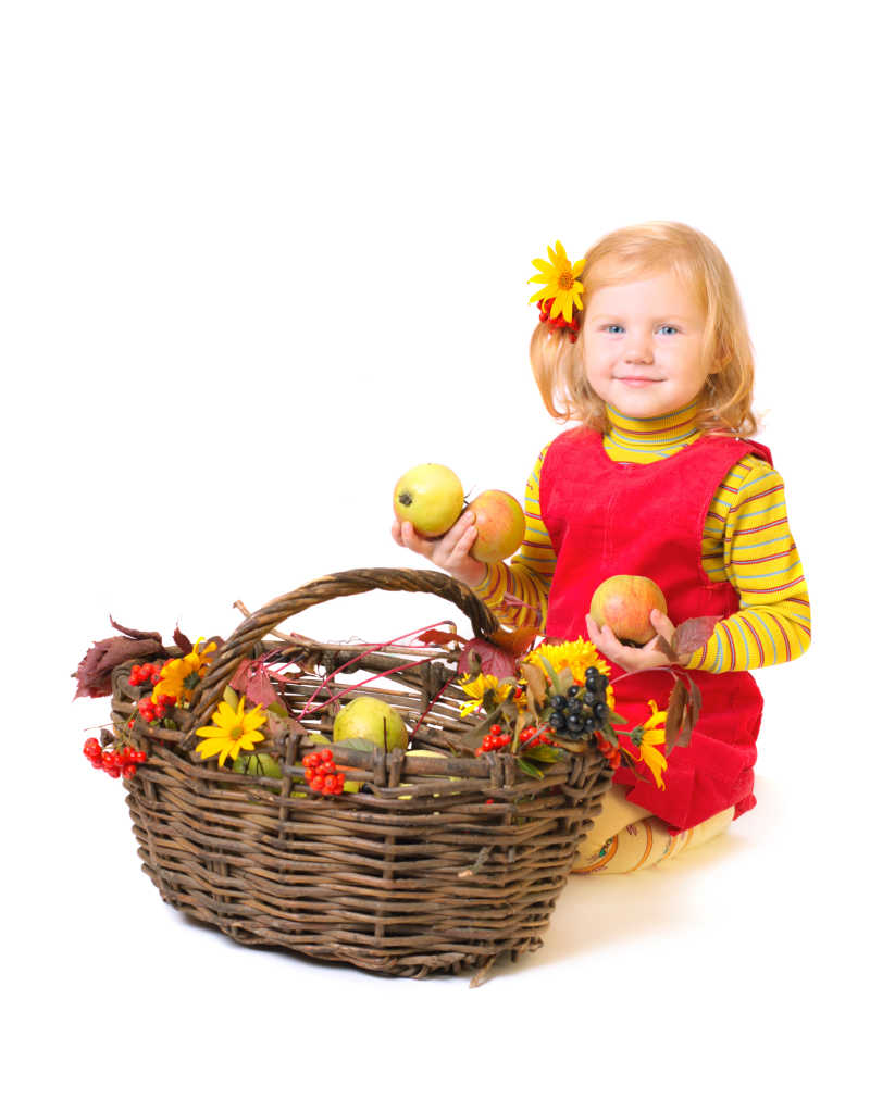 小女孩拿着苹果跪在竹篮的旁边