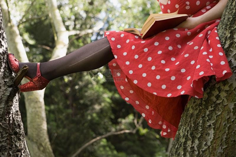 穿着红色裙子在树上读书的女人