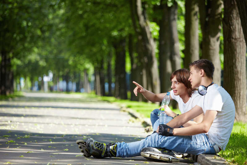 坐在公园小路边的两个年轻男人