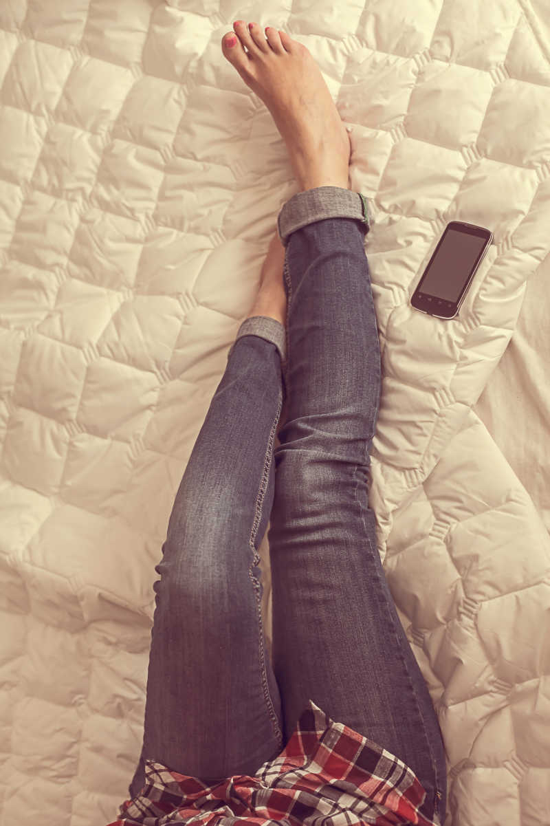 床上穿着牛仔裤的女人的腿