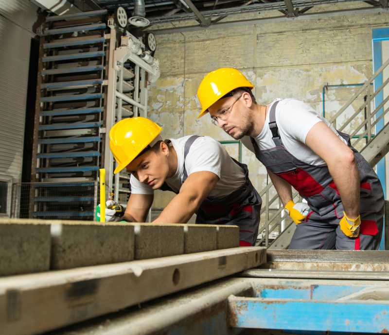 工人和工头戴安全帽进行工厂的质量检查