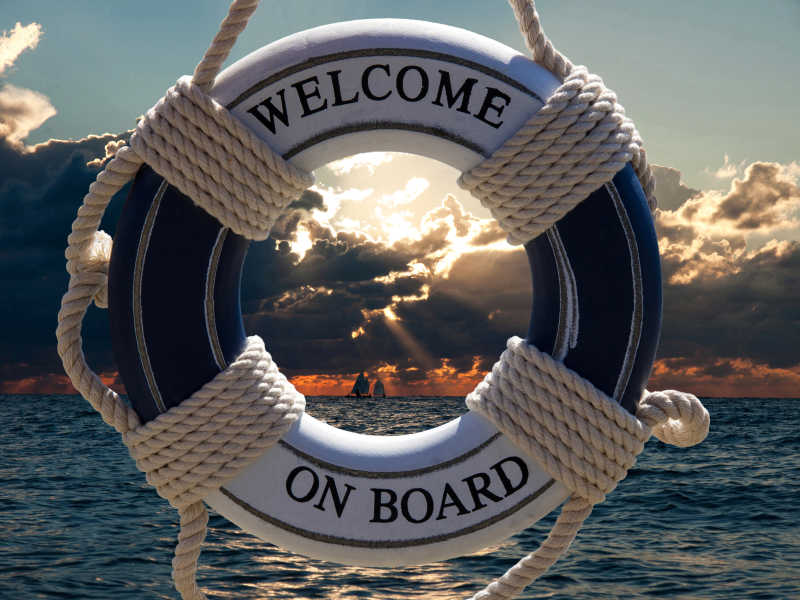日落时分写着欢迎上船标志的海上救生圈