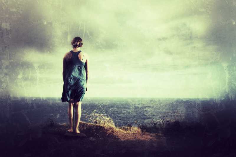 孤独的女人站在山顶上看着大海