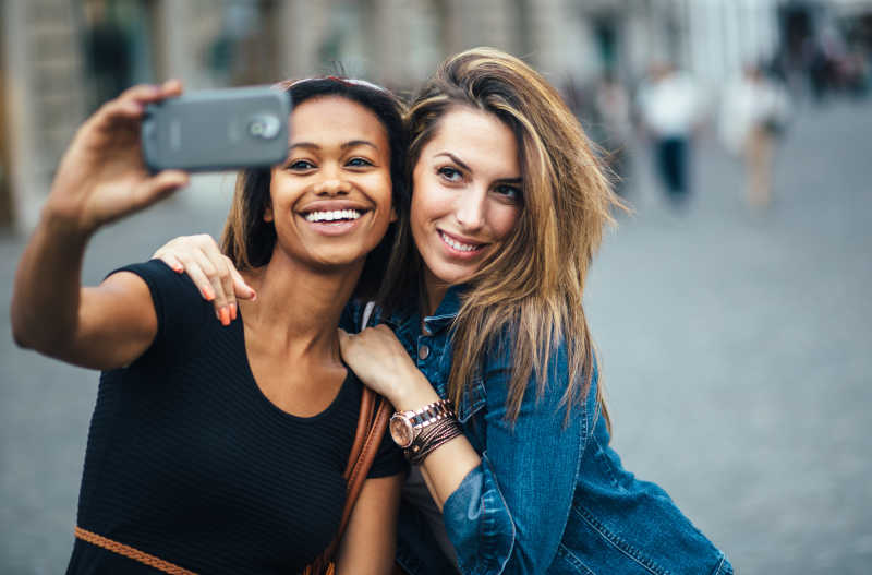 两个年轻女孩在街头用手机自拍